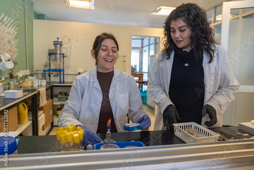 Obraz na plátne Two female scientists laughing while working with alcohol lamp in lab