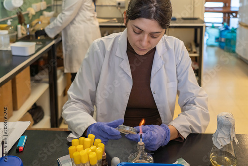 Fotografie Focused female scientist using alcohol lamp for aseptic technique
