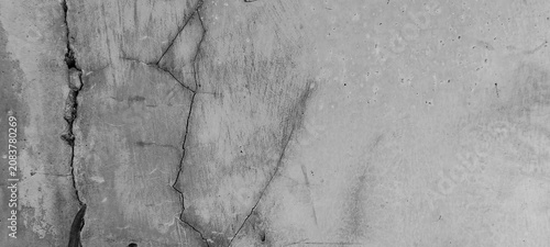 Bild auf Leinwand The texture of a cracked and weathered concrete wall set against a background of a worn-looking cement surface
