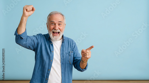 Smiling senior man in casual wear celebrating with fist raised and pointing excitedly