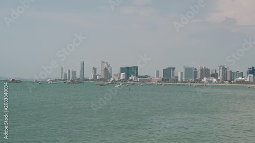 Wide daytime panorama of Pattaya's skyline viewed across the Gulf of Thailand, featuring calm turquoise water and the city's modern waterfront. Ideal for travel, tourism, and urban coastal concepts.