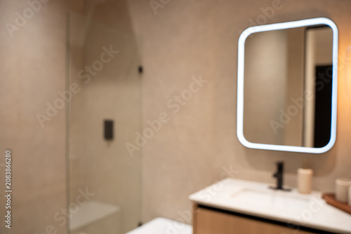 Blurred view of modern bathroom interior with illuminated mirror.