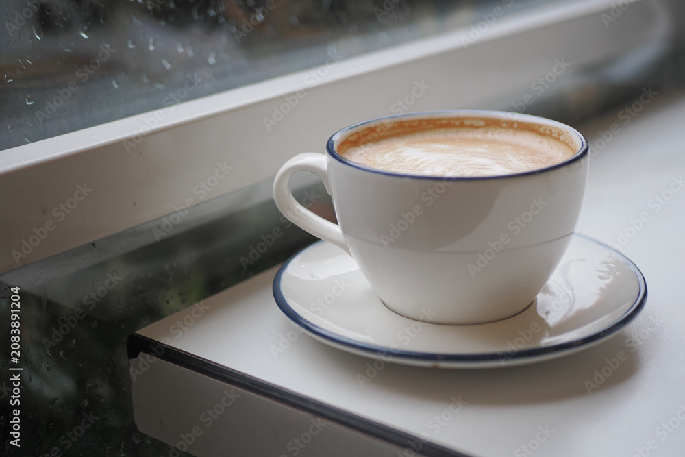 Naklejka premium Coffee cup sits on table near window during rainy day