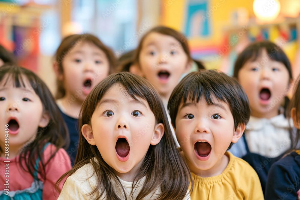 Fototapeta premium 保育園の教室で全員が口を開けて驚き顔をする日本人の男女幼児のグループ