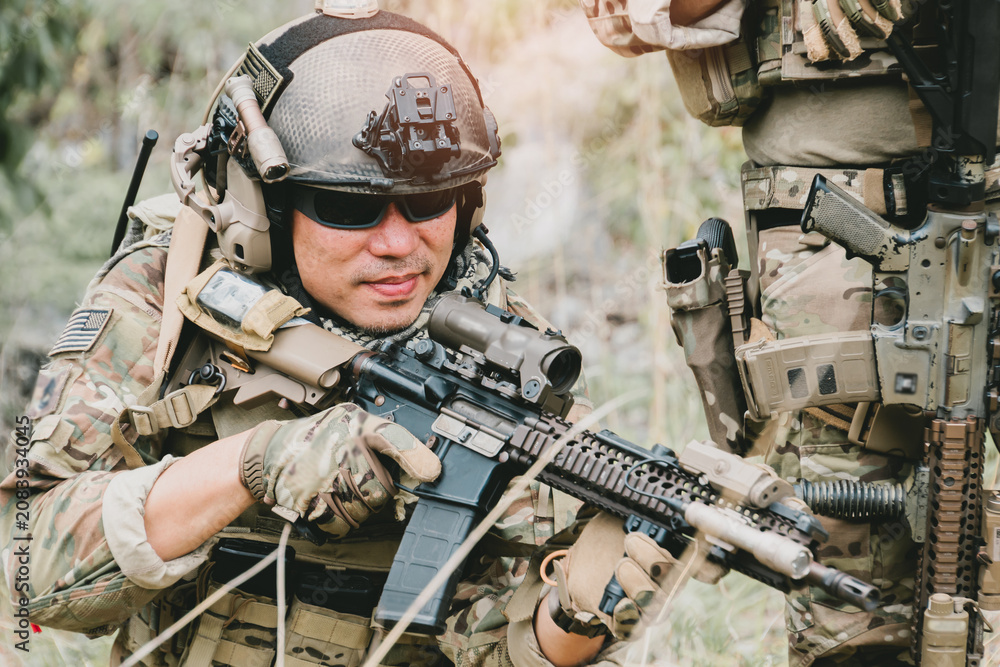 Fototapeta premium Outdoor military concept. Soldier aiming rifle in tactical gear during outdoor training exercise