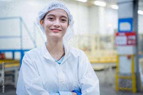 Obraz na plátne Smiling female quality control technician in white lab coat and protective hair
