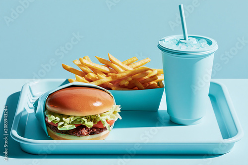 Minimalist fast food combo mockup featuring beef burger crispy french fries and cold soda drink cup on light blue tray background presentation