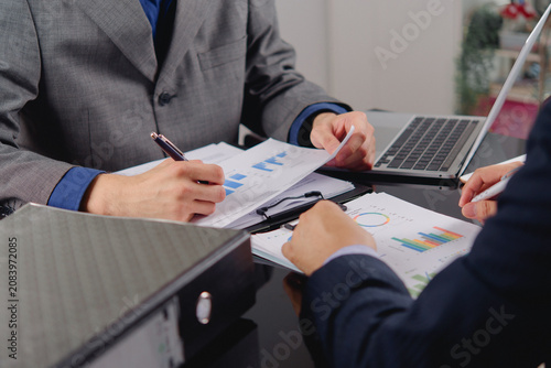 businessmen writing clipboard reviewing financial bar charts documents office desk corporate managers analyzing business data performance metrics accounting auditing paperwork planning investment