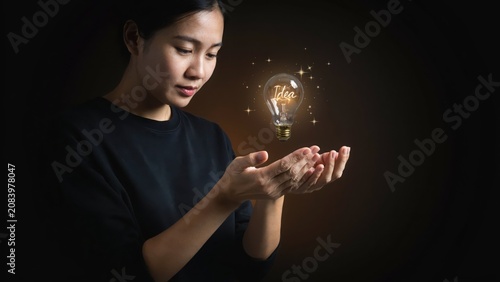 Young woman holding glowing light bulb with word idea, symbolizing creativity and innovative thought.