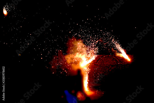 Fireworks Night Celebration – Pyrotechnic Sparks with Brick Structure and Silhouetted Figure Illuminated by Fiery Glow Concept