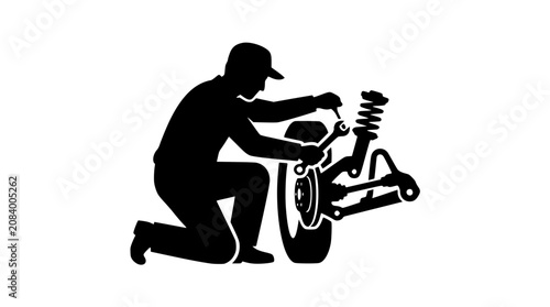 Silhouette of an auto mechanic repairing car wheel and suspension system