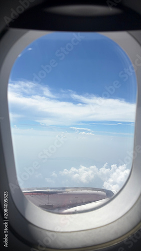 Принти на полотні View from an airplane window showing blue sky, white clouds, and a glimpse of the aircraft engine