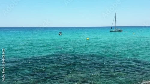 Crystal clear turquoise sea water and scenic rocky coast with sailing boats under a blue sky. summer vacation concept.