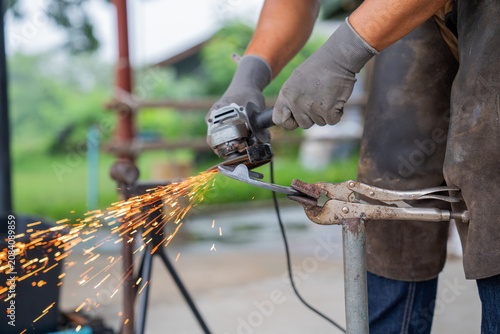Tableau sur toile Professional farrier using angle grinder on horseshoe with bright sparks flying,