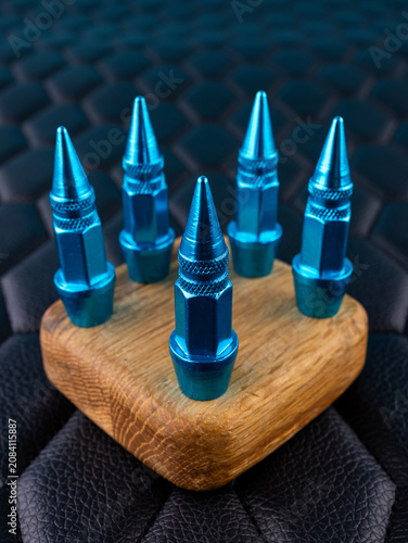 Close-up of blue metallic cap tips on a valve, spiked shape, against a black background.