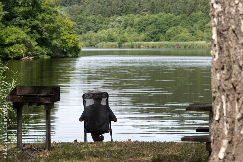 Obraz premium pêcheur assis relax vu de dos à l'étang
