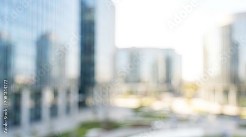 Blurred Modern City Background with Corporate Buildings and Bright Light. Abstract Bokeh Urban Backdrop.