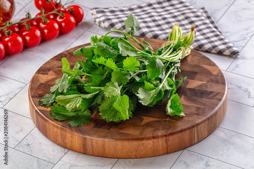 Принти на полотні Fresh cilantro on wooden cutting board with cherry tomatoes and checkered napkin