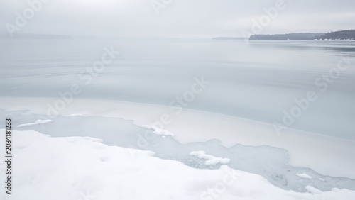 The edge of a winter lake where water transforms into milky ice.