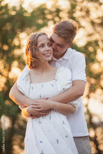 Canvas Print Young couple embracing tenderly in warm golden hour sunlight outdoors