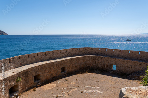 Tableau sur toile Historic stone fortress fortification with bastions and embrasures stands on coast by blue sea water under clear sky on Spinalonga island Crete Greece