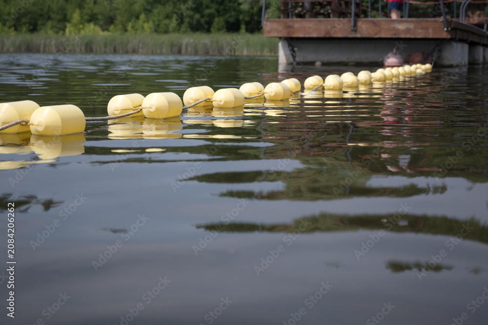 Obraz premium Buoys marking the area of ​​a supervised swimming zone. A lakeside swimming area in summer. 