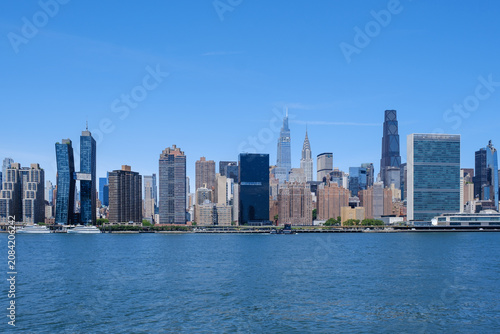 Photography Panoramic daytime view of the Midtown Manhattan skyline featuring the UN headquarters and modern skyscrapers from the East River, New York