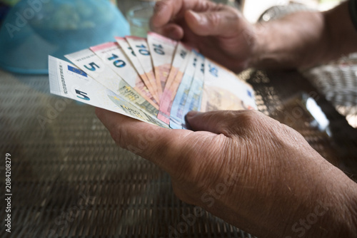 Fotografie An elderly man holds euro banknotes in his hands.