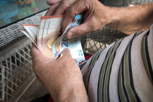 Fotografie A pensioner is counting euro banknotes.