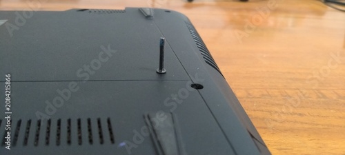 Photos Close-up of laptop disassembly process, single screw sticking out