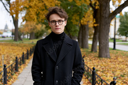 Young man stands on path in autumn park