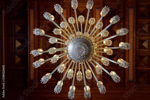 Foto Low angle view of a magnificent luxury crystal chandelier on a carved wooden cei