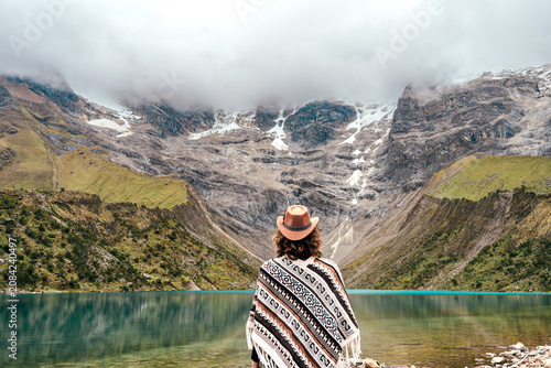 Foto Rear view of a woman in traditional poncho and hat looking at the blue lake of H