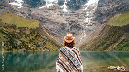 Foto Rear view of woman in traditional Peruvian poncho and hat contemplating Humantay