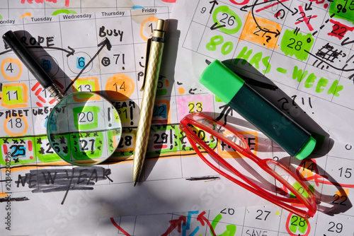 Calendar with business appointments and deadlines,pens,and paperwork on  messy workplace. Business concept beat the clock, overworked, stress. Free copy space
