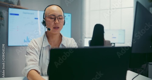 Young Asian female agent talking on phone headset consulting client online in call center office. Corporate customer service, technical support, remote tech operator, business team help desk concept.