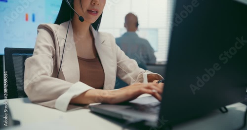 Young Asian female agent talking on phone headset consulting client online in call center office. Corporate customer service, technical support, remote tech operator, business team help desk concept.