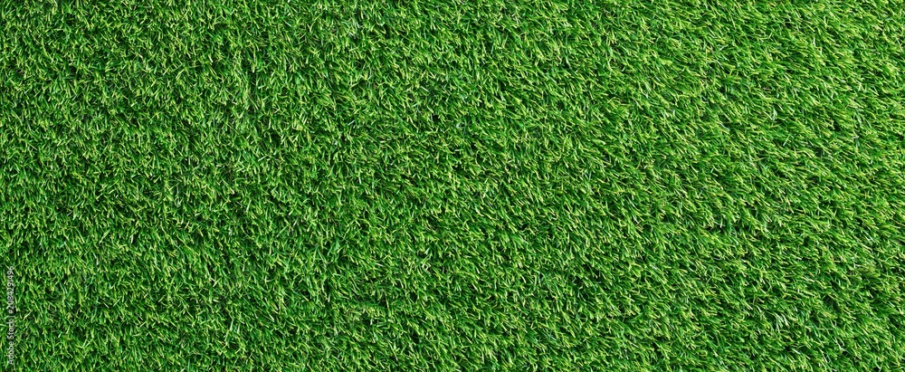 Obraz premium A vibrant green artificial turf field viewed from above, highlighting smooth texture and rich color ideal for outdoor sports.