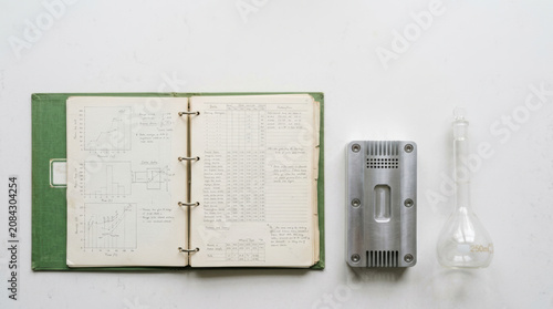 Laboratory notebook medical research notes graphs and measurements open binder with lab equipment