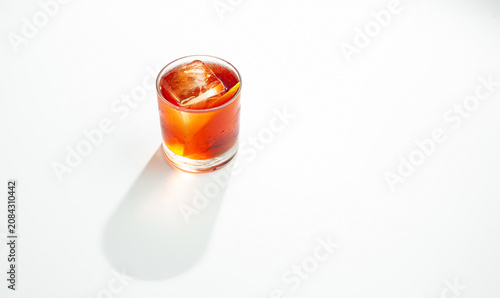 Orange Cocktail with Ice Cube and Citrus Peel in Rocks Glass on White Background with Copy Space