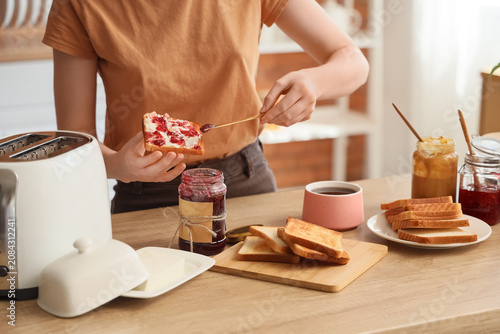 Canvastavla Person spreading jam on toast in kitchen