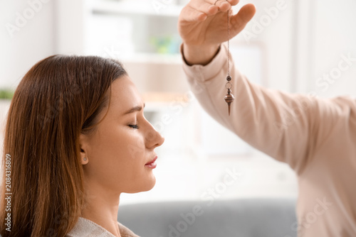 Obraz na płótnie Male psychologist with pendulum hypnotizing woman in office, closeup