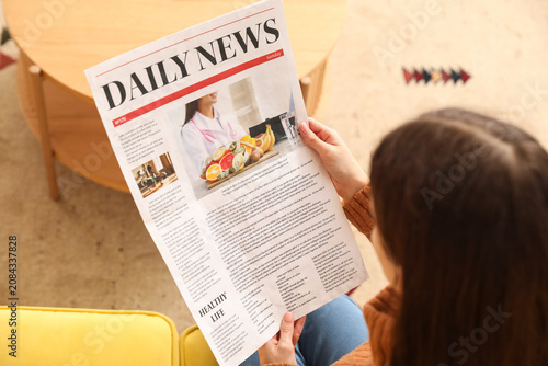 Young woman reading newspap...
