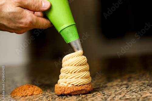 Obraz na płótnie Pastry chef piping cream onto a gourmet dessert with a pastry bag
