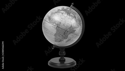 A black and white globe on a stand against a black background, showcasing a map of the world