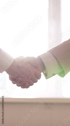 Camera moving during a business handshake with a cinematic lens flare against a bright light