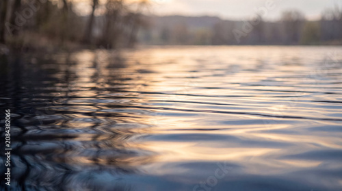 Tableau sur toile Gentle water ripples reflecting sunset light on a calm lake