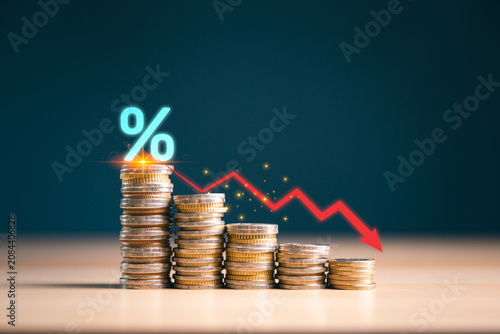 Photos Declining coin stacks with percent symbol and red downward arrow show falling interest rates, financial loss, recession risk, market downturn, savings decline and economic crisis concept