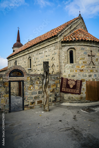 Картината върху платно Ancient stone Orthodox church with red tiled roof, domed steeple, and traditional rug in Tbilisi, Georgia
