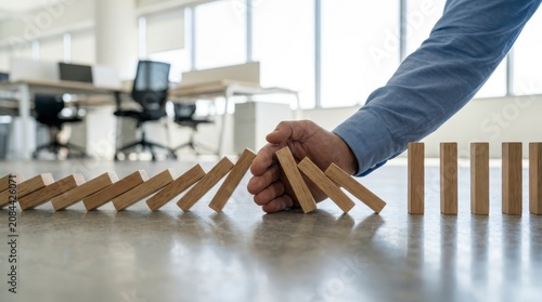 Hand stopping domino effect in office